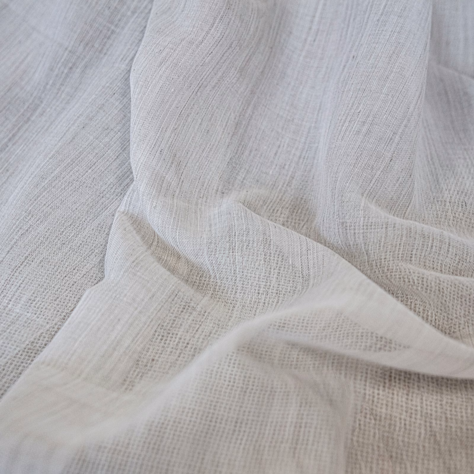 Warm ecru open gauze weave draped in soft, translucent folds