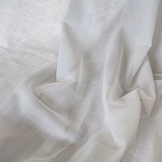 Optic-white sheer fabric with a fine open grid weave draped in soft folds