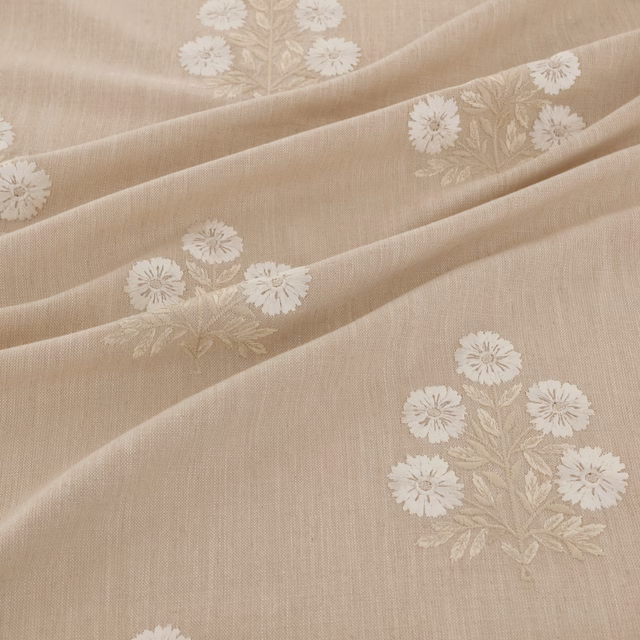 Warm beige woven fabric with ivory floral sprays arranged across softly draped folds