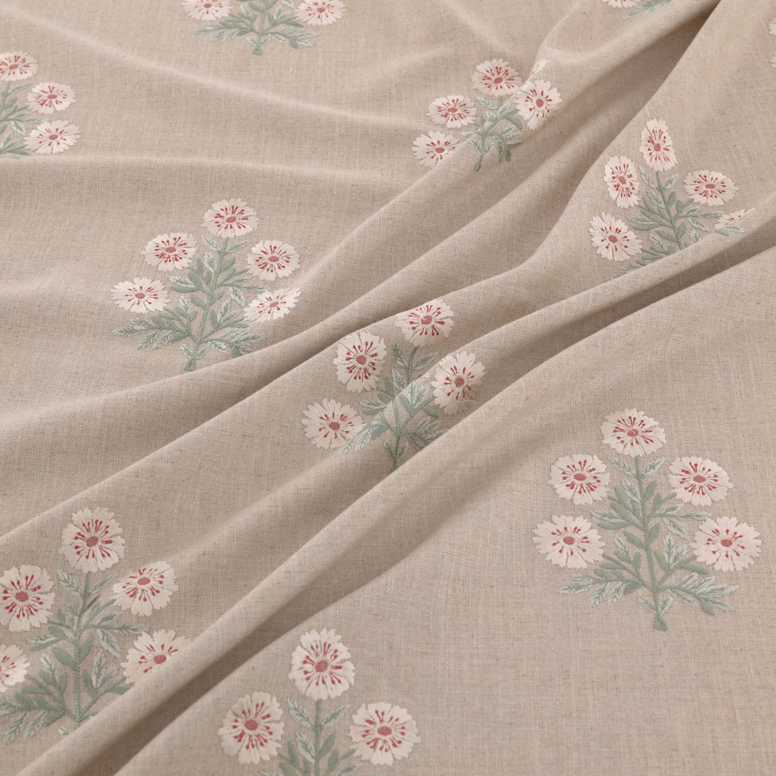 Pale taupe woven ground with blush daisy clusters and sage foliage in soft folds