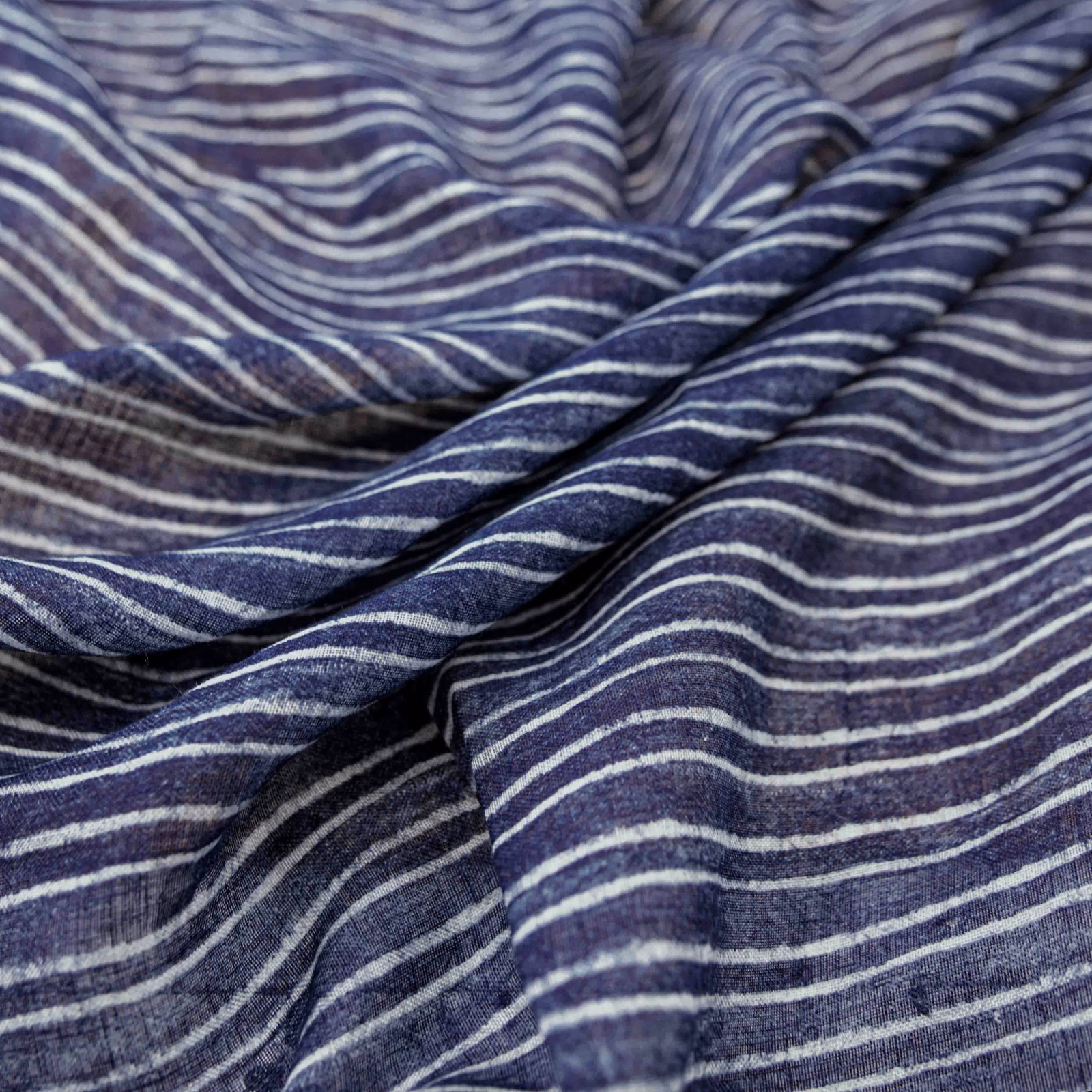 Deep indigo fabric with pale irregular wave stripes and softly gathered woven texture