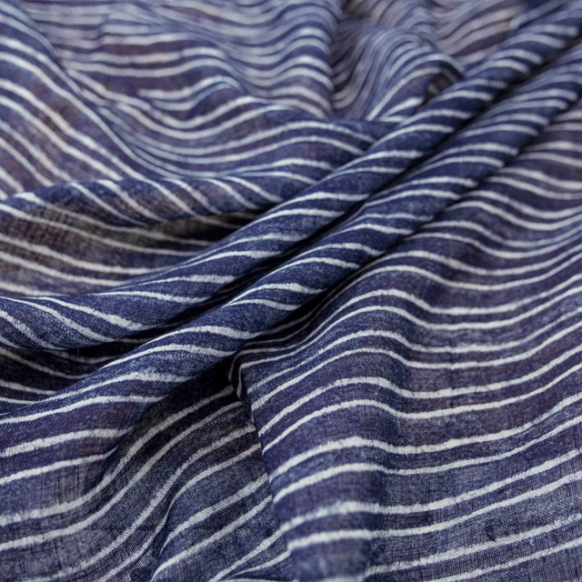 Deep indigo fabric with pale irregular wave stripes and softly gathered woven texture