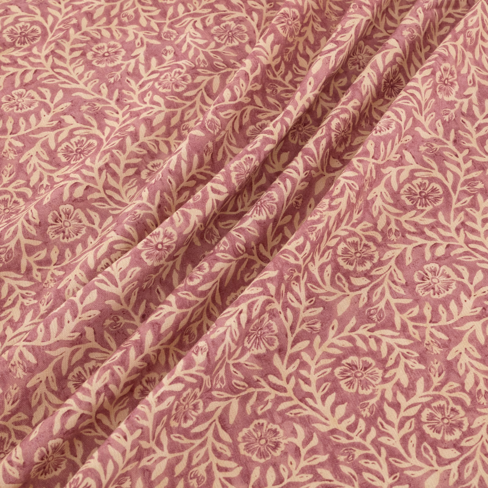 Dusty rose floral fabric with cream vines and folded botanical drape
