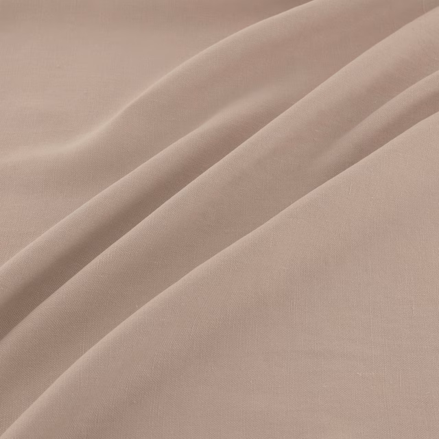 Warm buff-beige plain weave fabric falling in soft, fluid diagonal folds