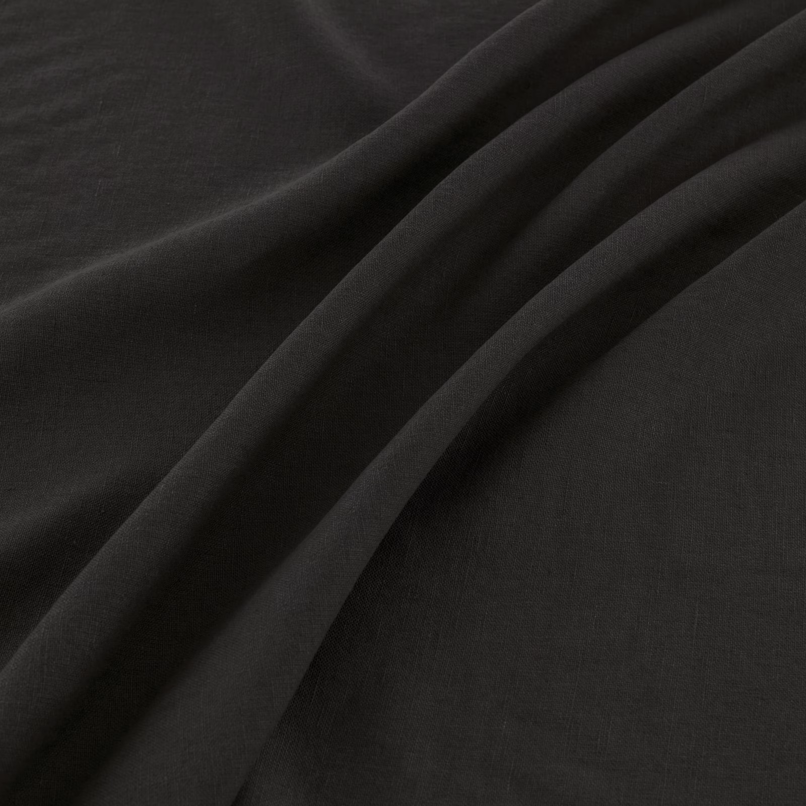 Near-black coal fabric with a fine woven surface, shown in deep fluid folds