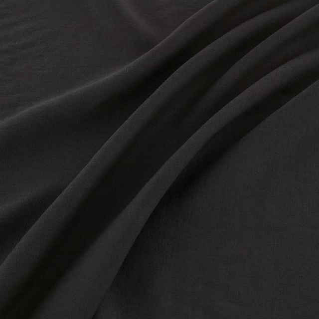 Near-black coal fabric with a fine woven surface, shown in deep fluid folds