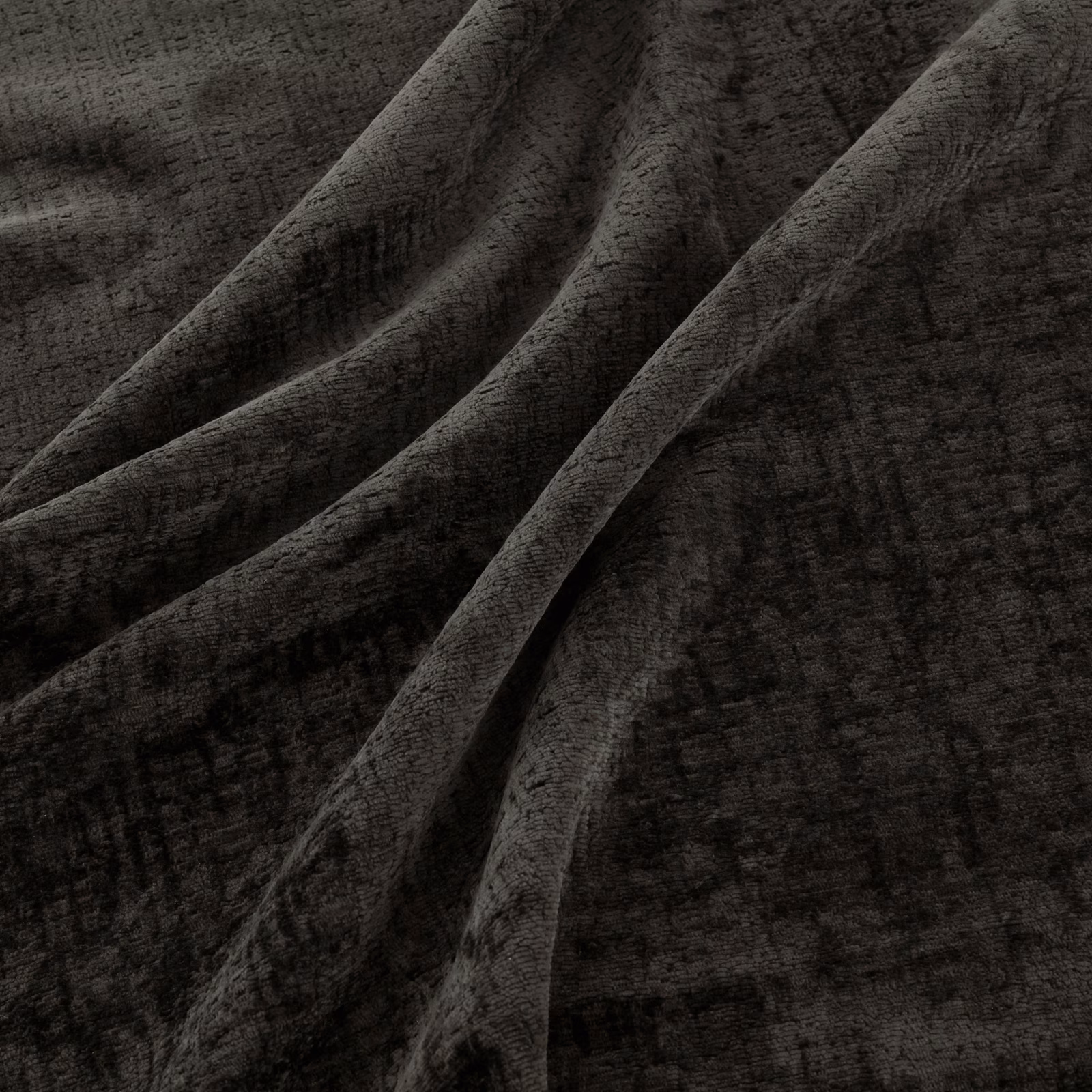 Dark charcoal fabric with distressed gridded texture folding into deep shadowed pleats
