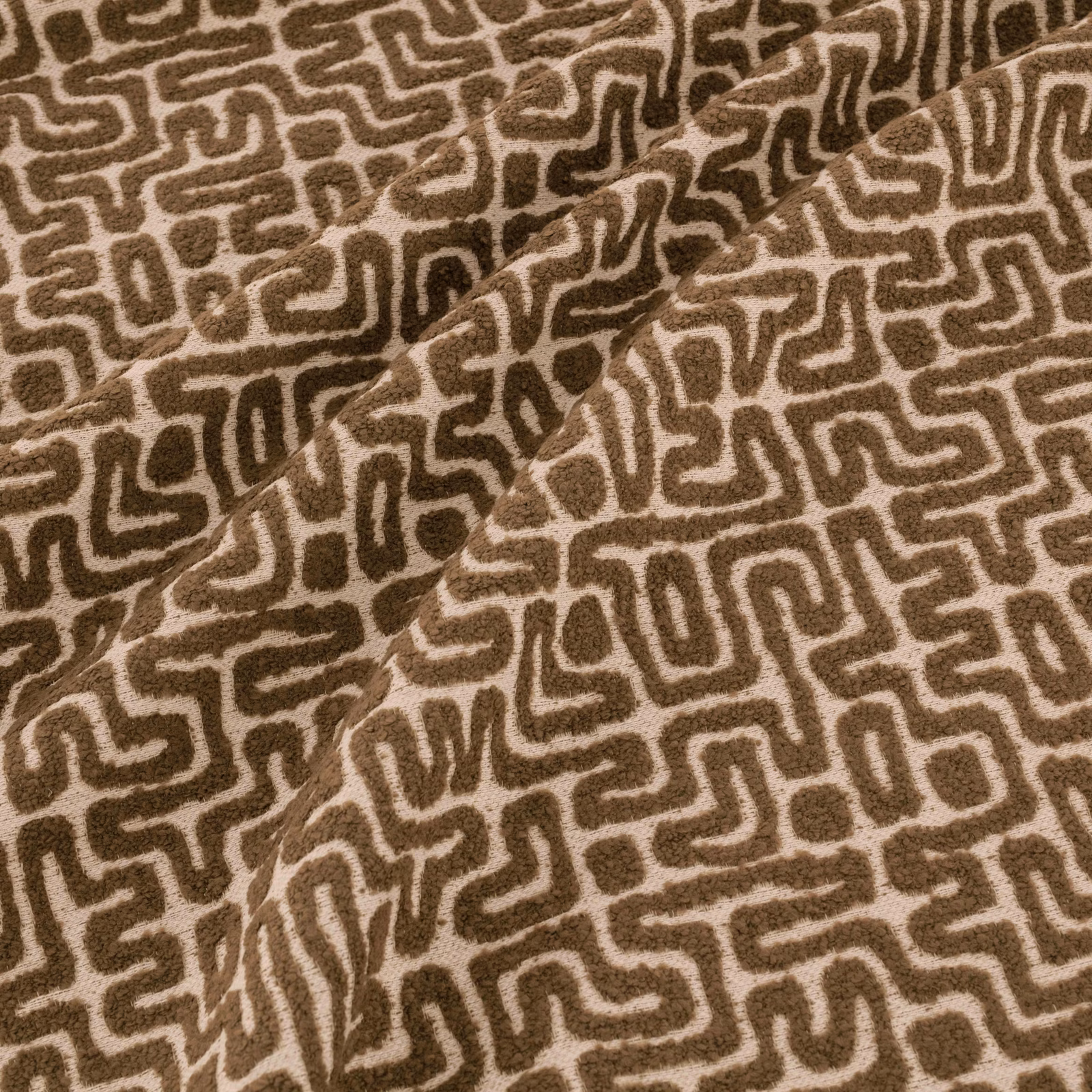 Warm earth-brown fabric with cream maze-like lines and softly textured folds