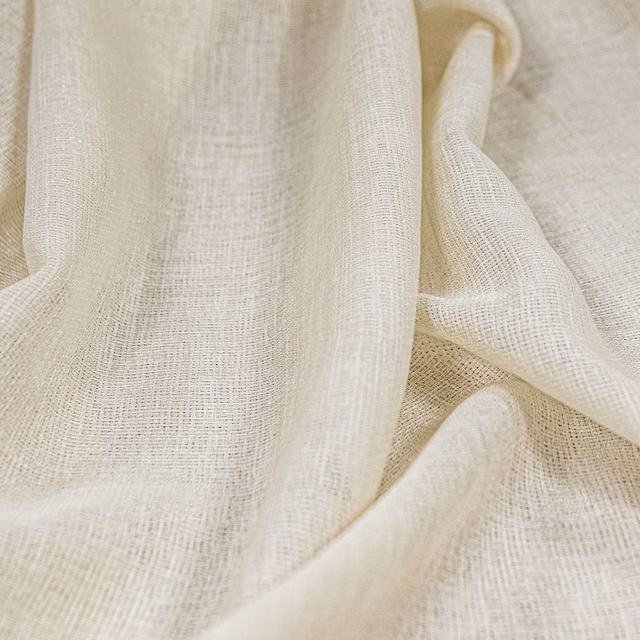 Warm ivory cream fabric with a fine open plain weave draped in soft folds