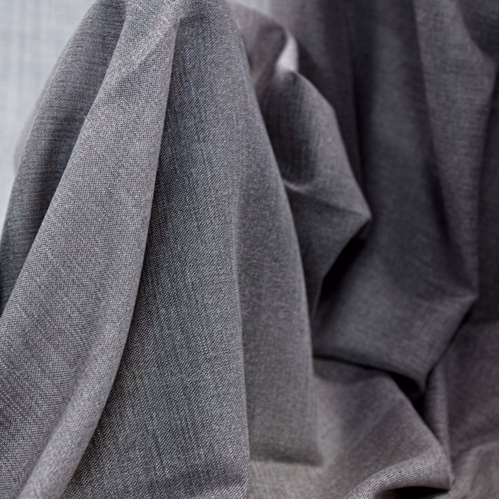 Cool pebble-grey woven fabric folded into softly shaded, substantial pleats