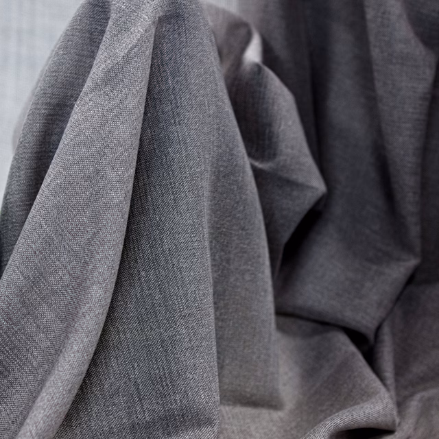 Cool pebble-grey woven fabric folded into softly shaded, substantial pleats