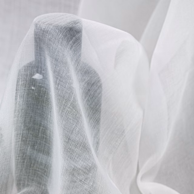 Sheer white Naousa fabric draped in folds, showing a fine gauze weave