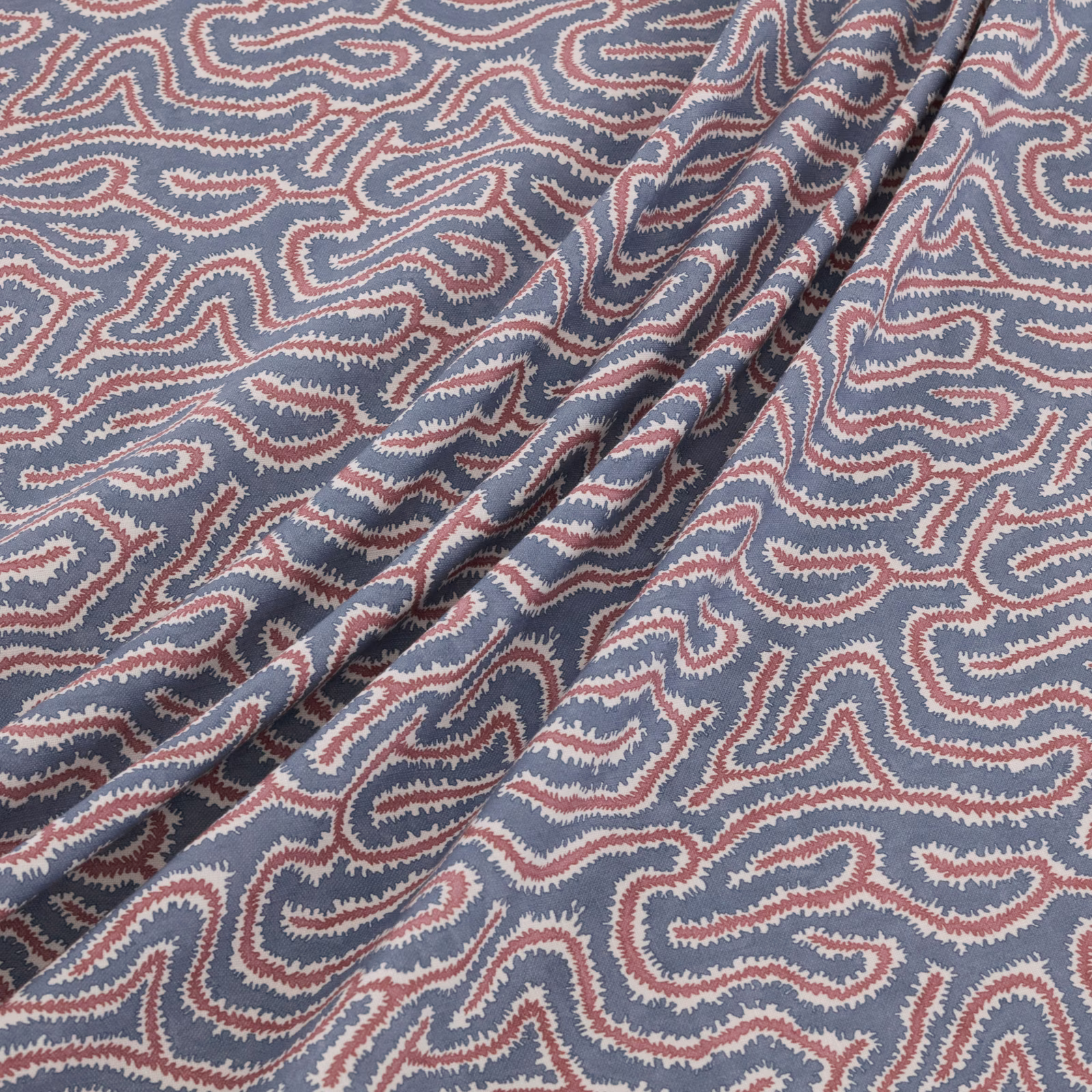 Dusty blue woven paisley fabric with ivory and muted red details in soft folds