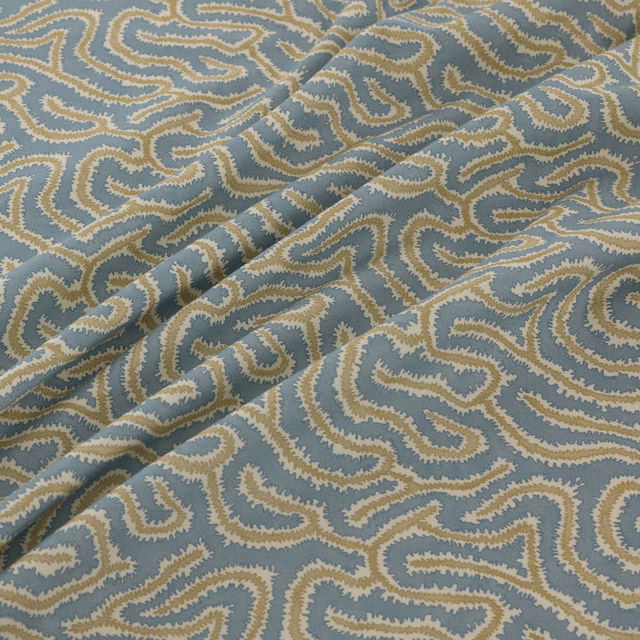 Blue-grey woven fabric with sandy cream meanders and a folded diagonal drape