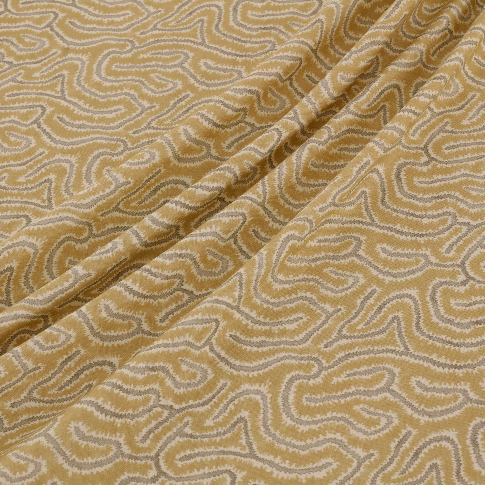 Ochre-gold woven fabric with cream sinuous motifs and softly folded texture