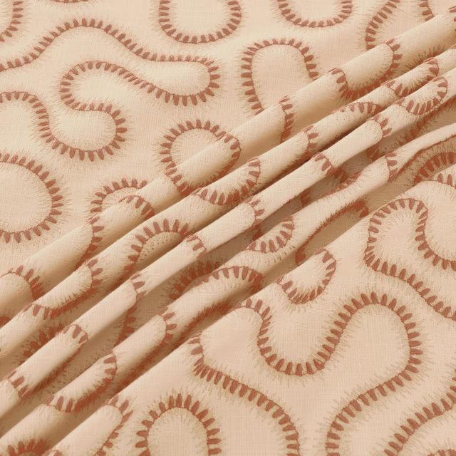 Warm ivory woven fabric with terracotta paisley loops and soft folded texture