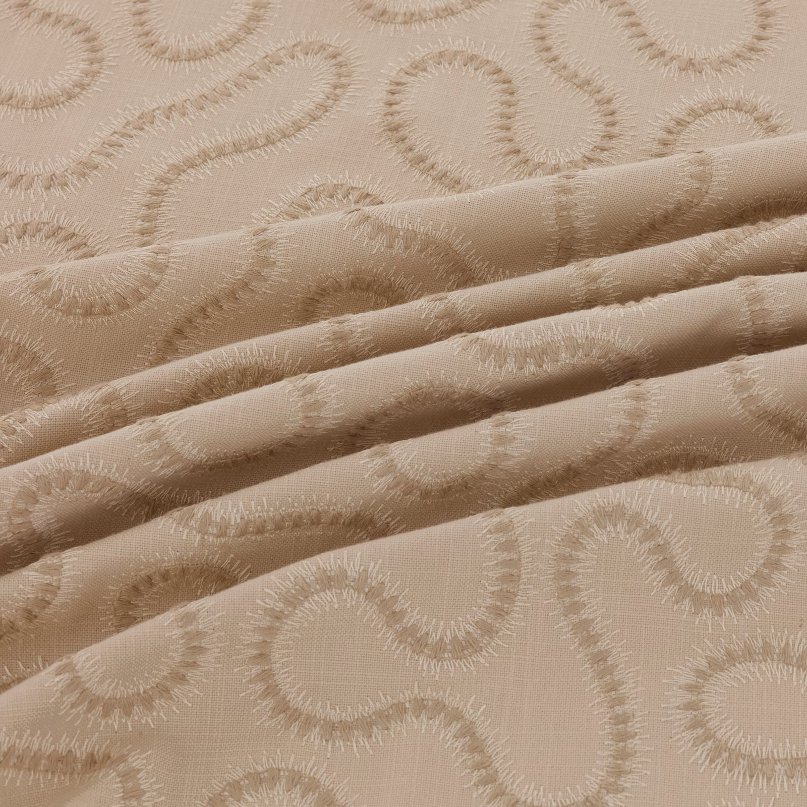 Warm taupe-beige fabric with raised scrolling paisley motifs and folded woven texture