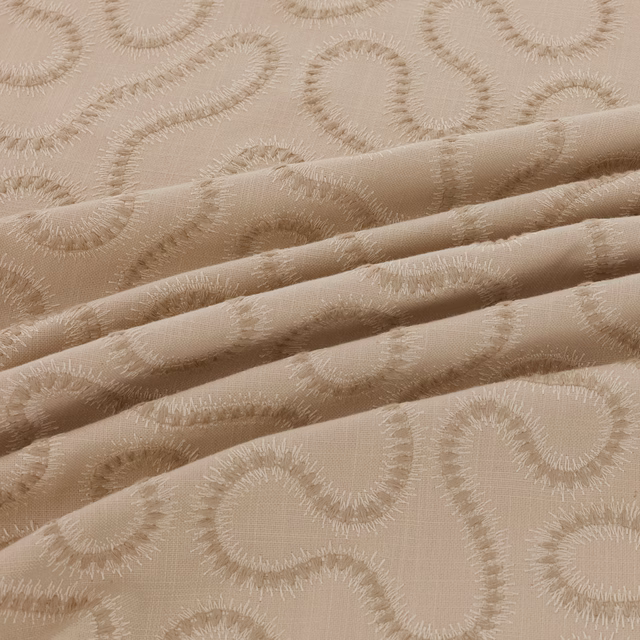 Warm taupe-beige fabric with raised scrolling paisley motifs and folded woven texture