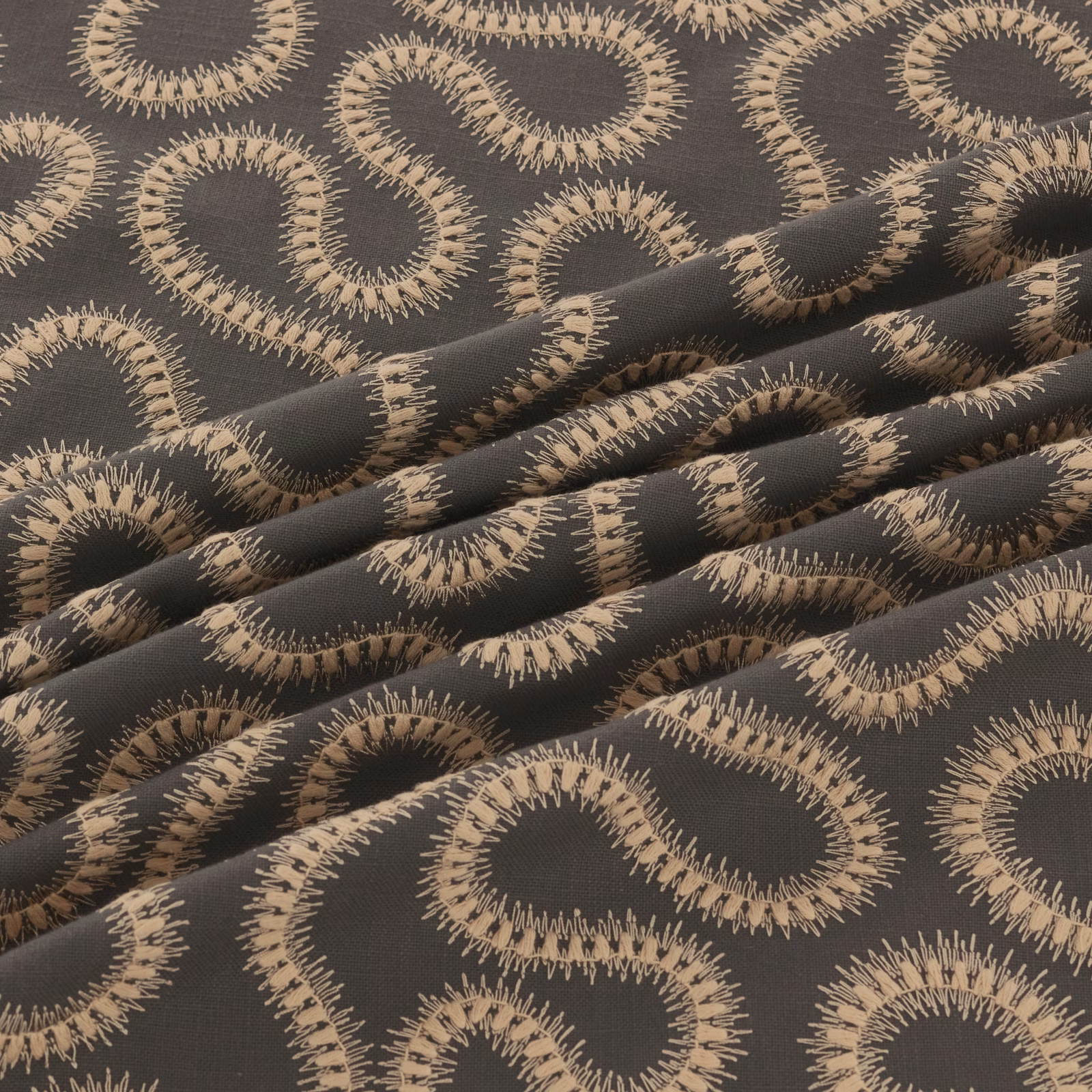 Charcoal woven fabric with large taupe looping motifs and fringed textured edges