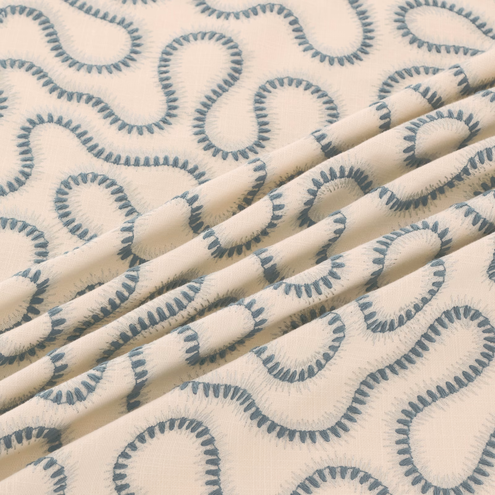 Cream woven fabric with cool blue-grey looping motifs and soft folded texture