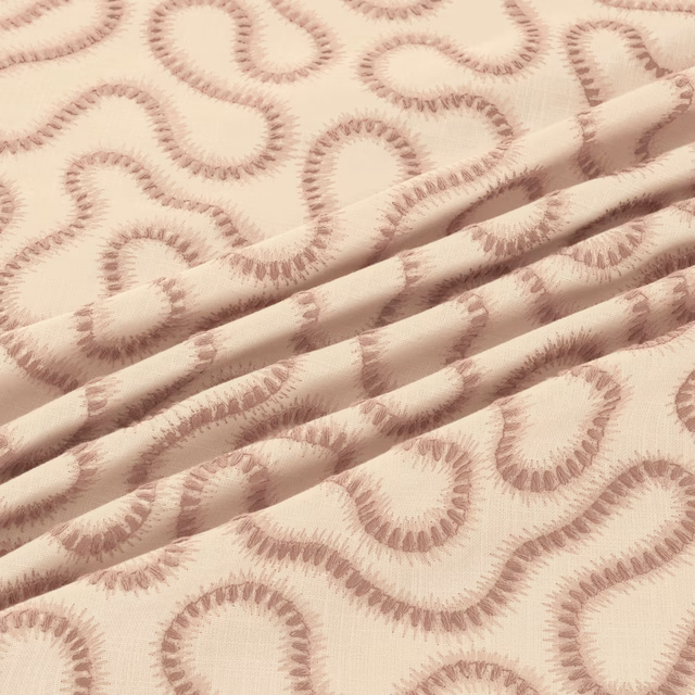 Warm cream woven fabric with dusty blush looping motifs and softly ridged texture