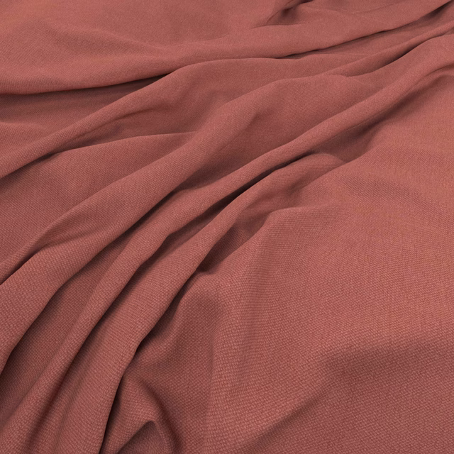 Muted brick-red woven fabric with soft folds and fine plain texture