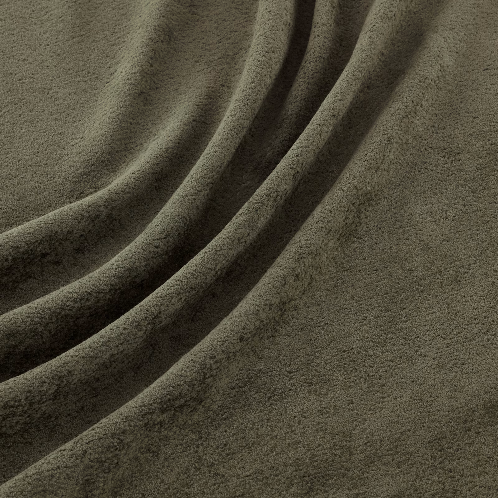Close view of muted olive basil-green velvety pile falling into deep diagonal folds