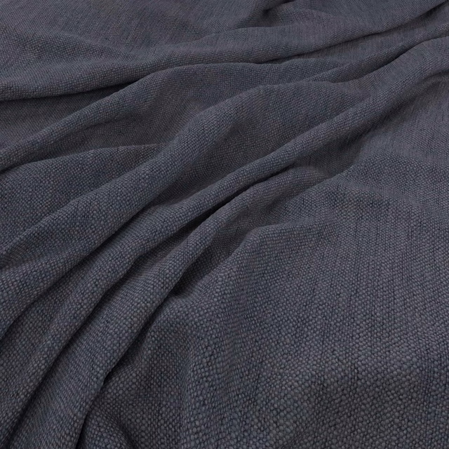 Close-up of dark denim blue-grey fabric with fine pebbled weave in gathered folds