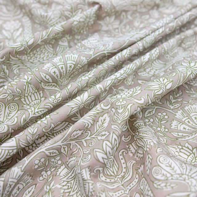Muted avocado botanical and paisley motifs on dusty blush fabric in soft folds