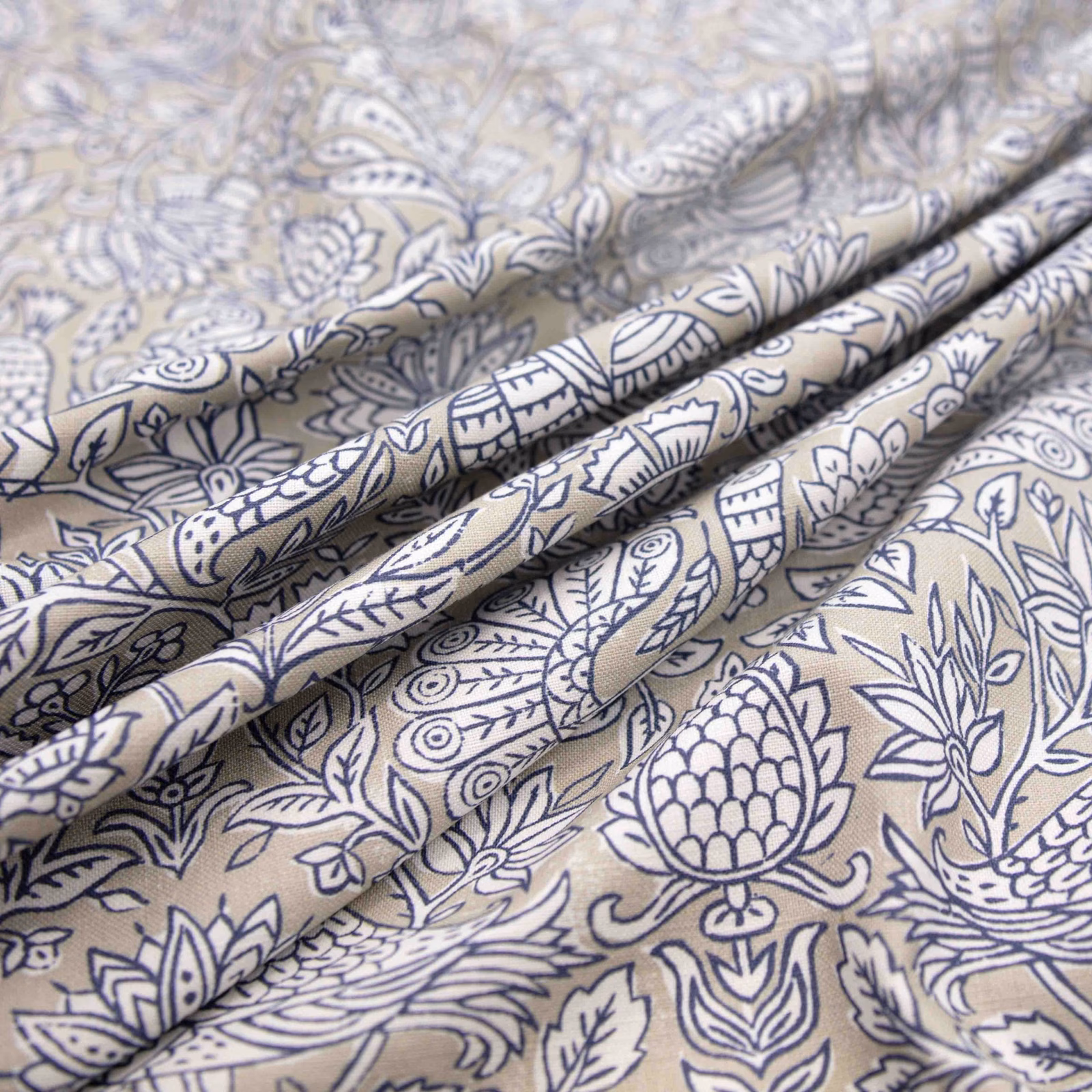 Warm corn-silk fabric with navy paisley, botanical motifs and softly folded texture