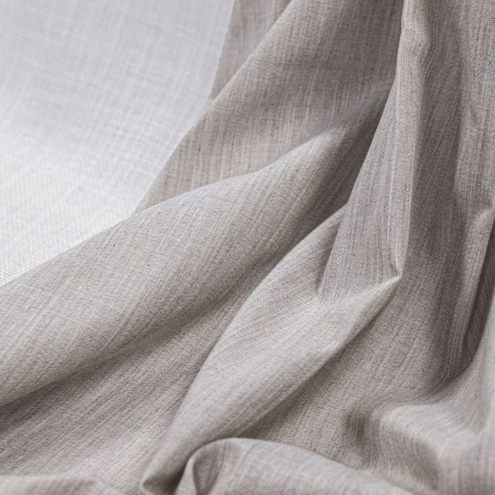 Warm greyed ecru fabric with fine plain weave arranged in soft folds