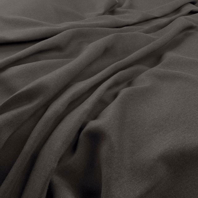 Deep charcoal-grey plain fabric falling in soft, fluid folds with a fine texture