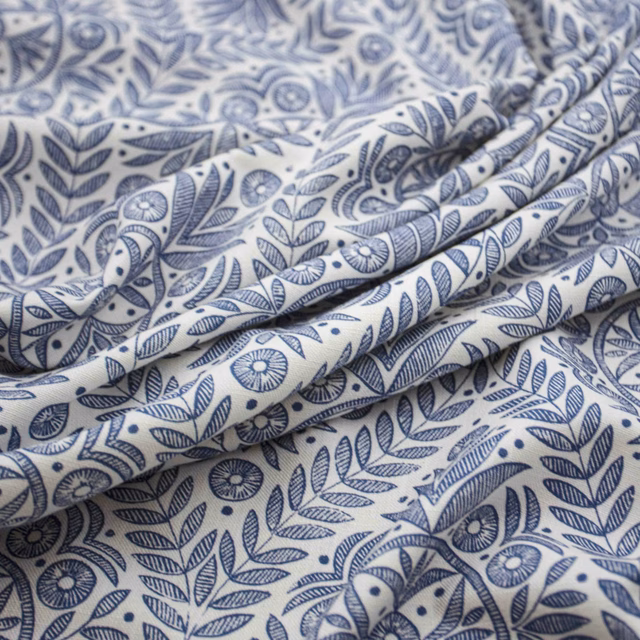 Warm cream fabric with blue botanical sprigs, flowers and softly folded texture
