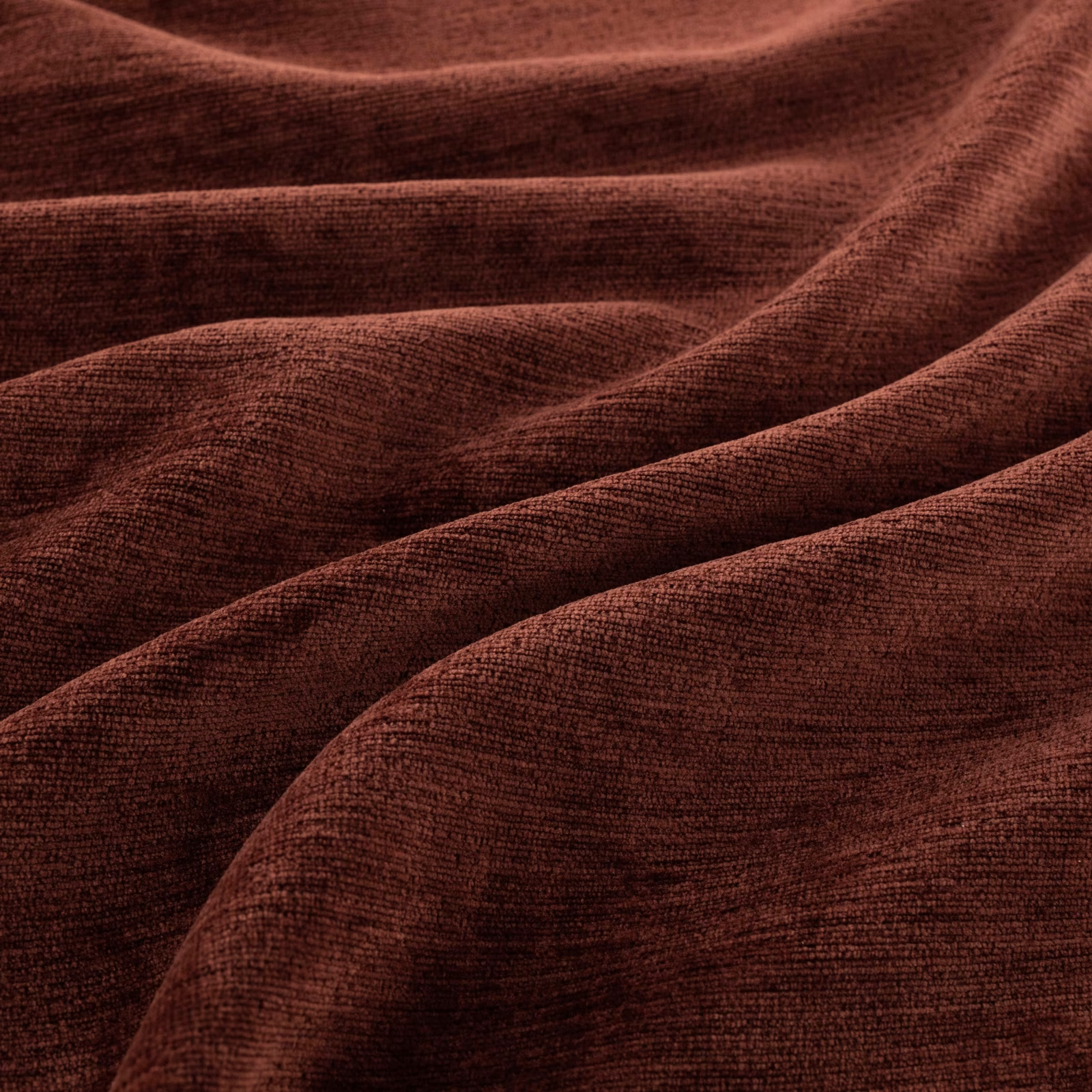 Deep chilli red-brown ribbed fabric with velvety pile folded into soft, shaded waves