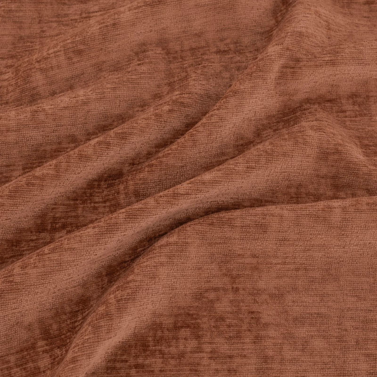 Warm kiln-terracotta fabric with fine ribbing, cloudy shading and deep diagonal folds