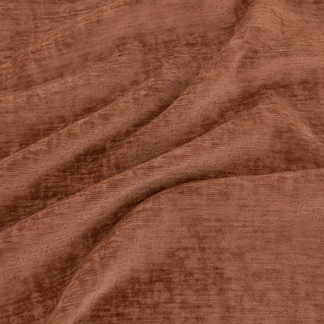 Warm kiln-terracotta fabric with fine ribbing, cloudy shading and deep diagonal folds
