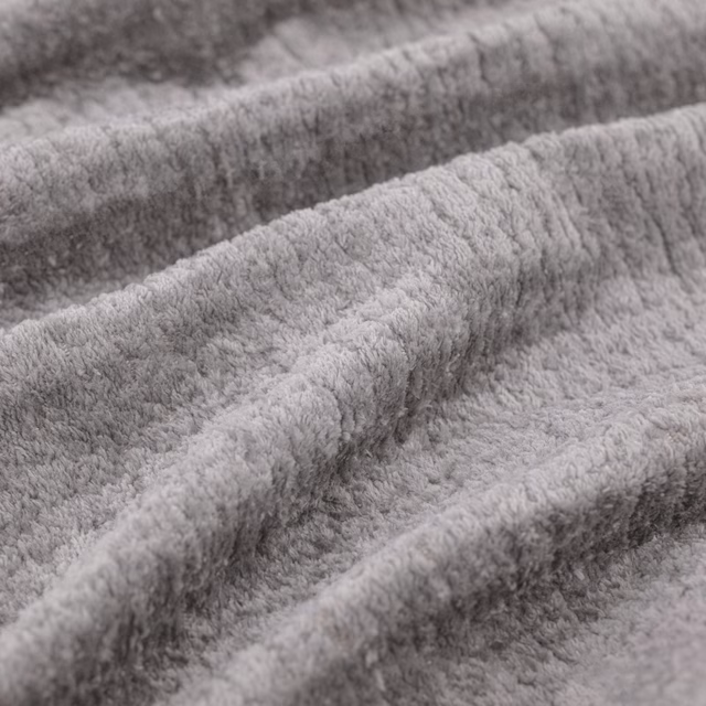 Soft cool-grey plush fabric folded into ridges, showing dense tactile pile and shaded texture