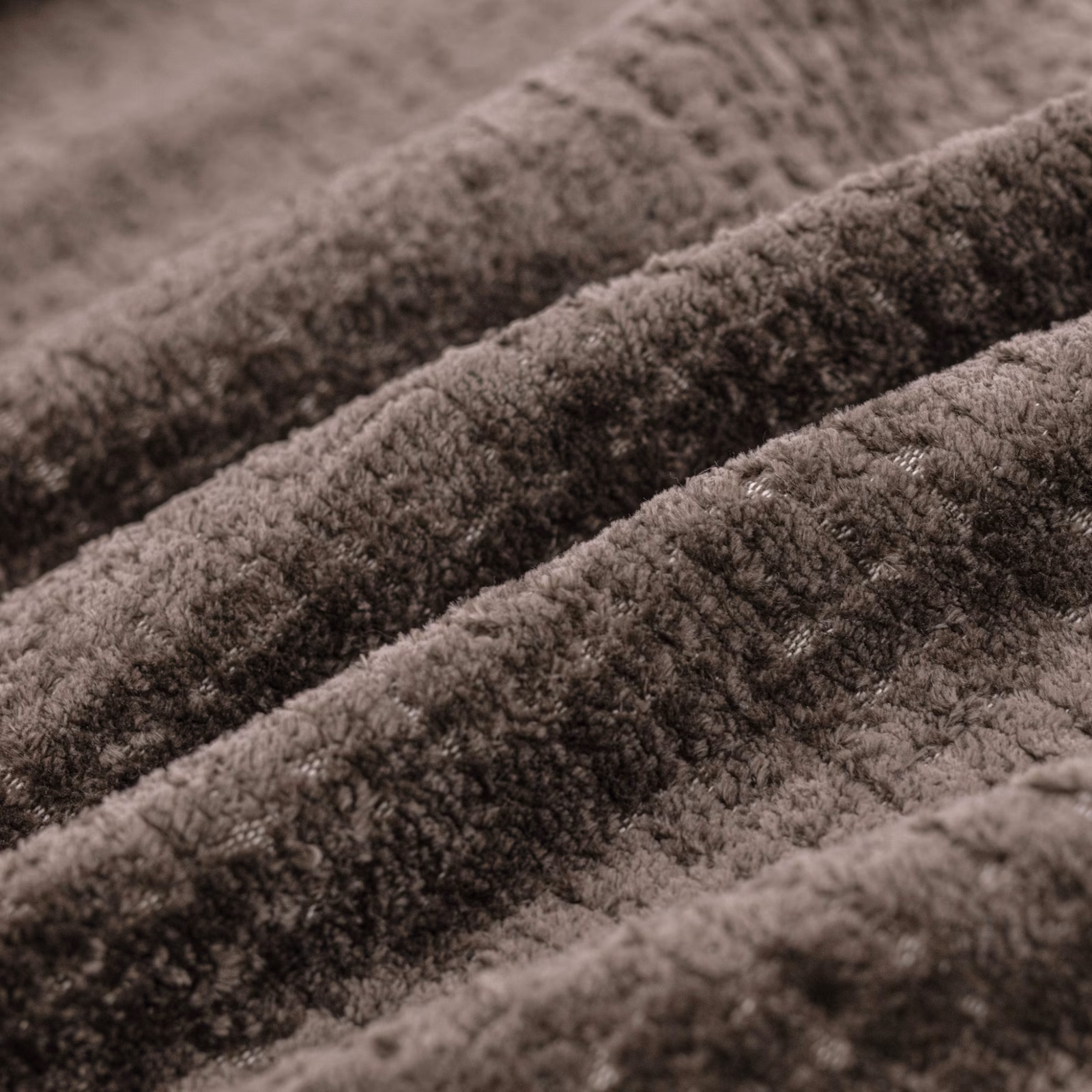 Close-up of warm taupe-brown plush pile forming soft, shadowed fabric ridges