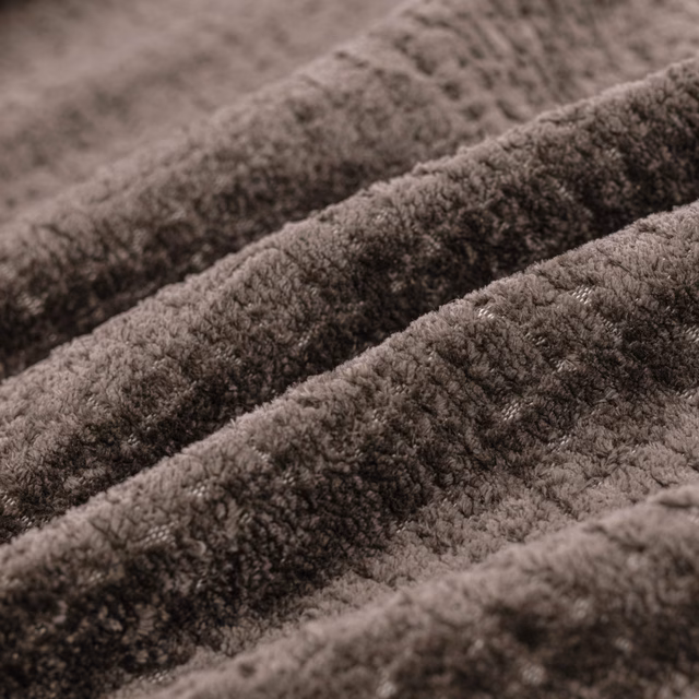 Close-up of warm taupe-brown plush pile forming soft, shadowed fabric ridges