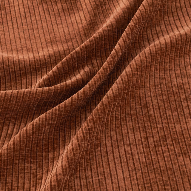Warm hazel-brown ribbed fabric folded to show darker textured pleats