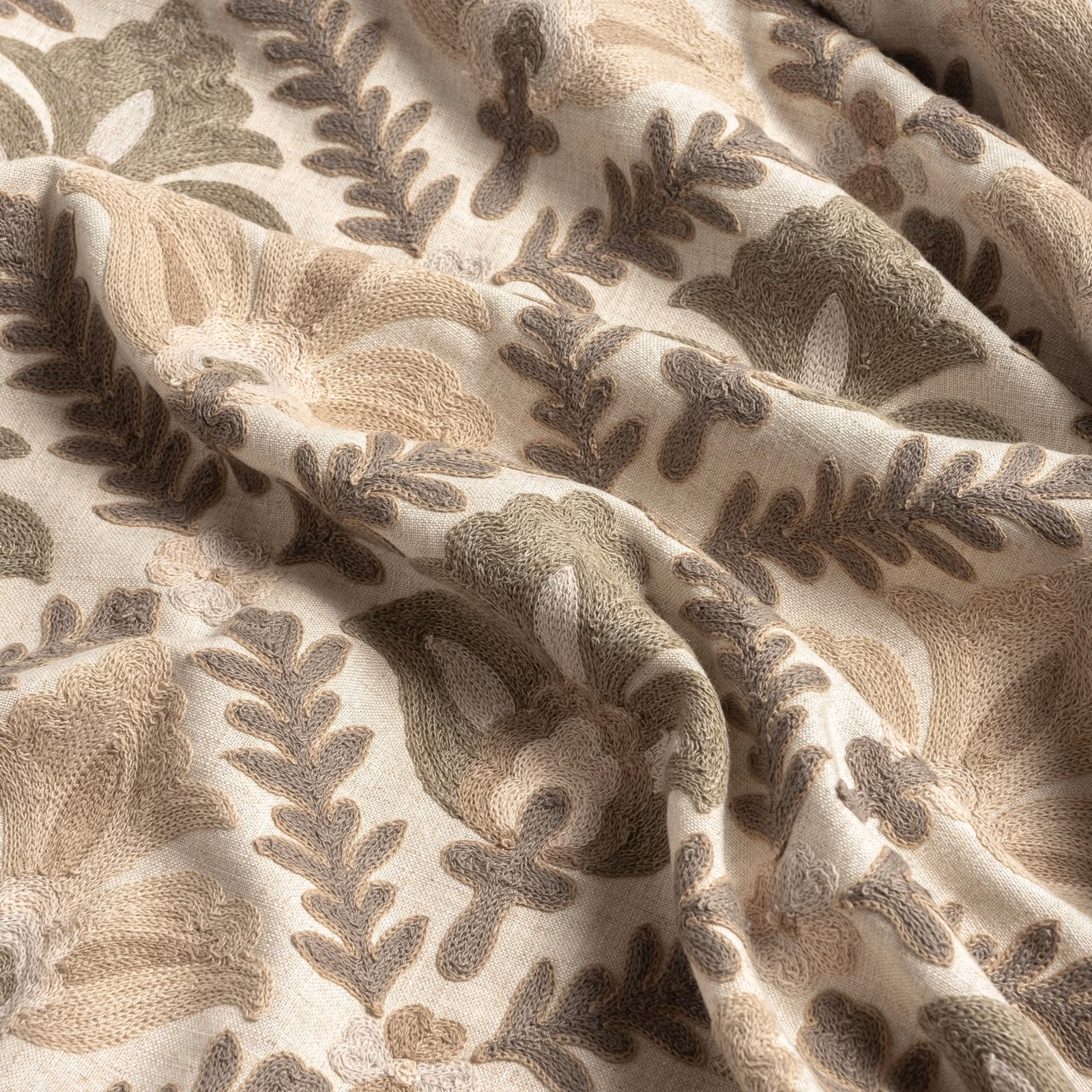 Warm parchment fabric with taupe leafy branches and rounded floral motifs in soft folds