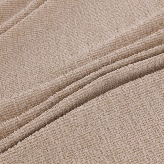Chalky beige woven fabric showing fine flecked texture across soft folded ridges