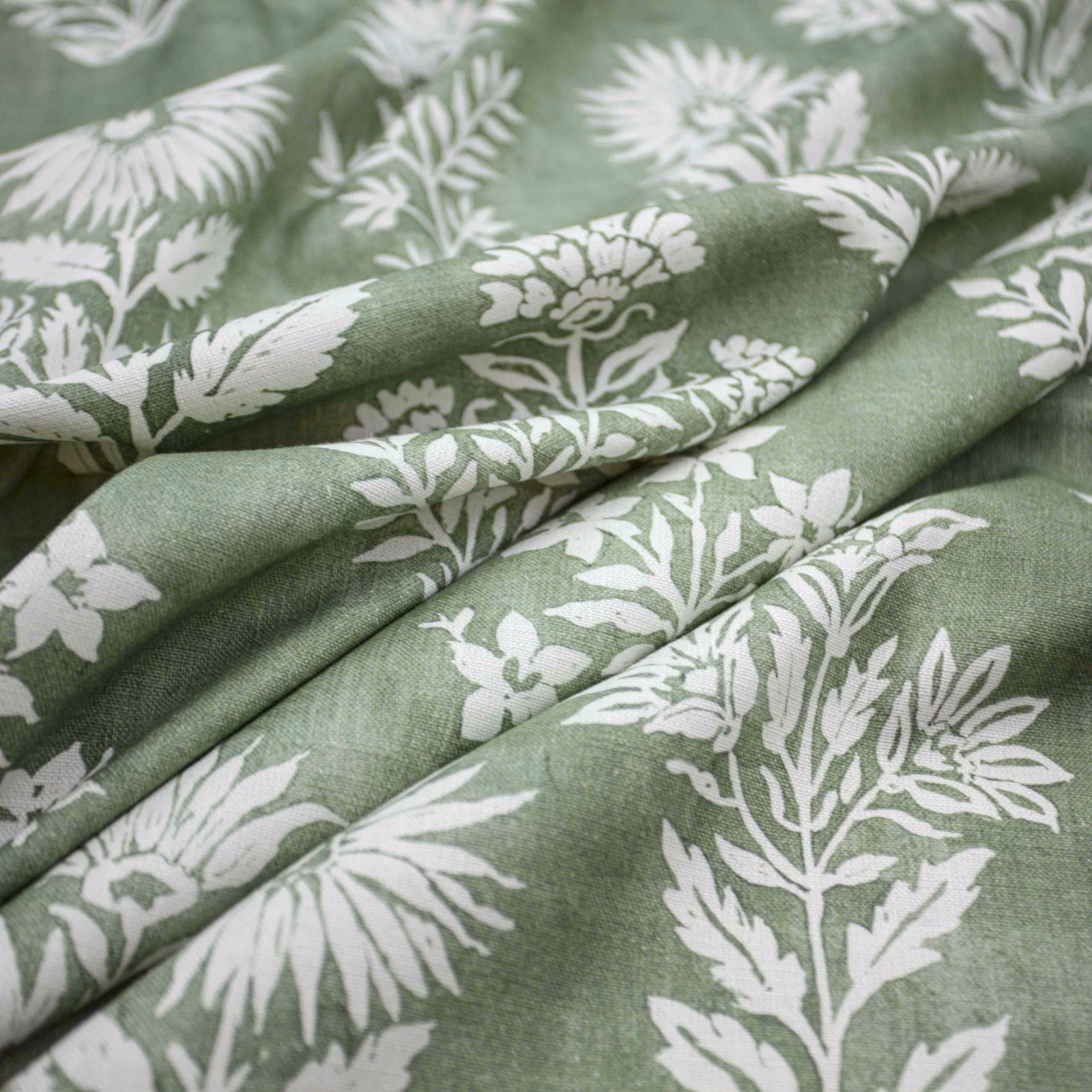 Muted celadon-green cloth with white leafy botanical flowers and softly textured folds