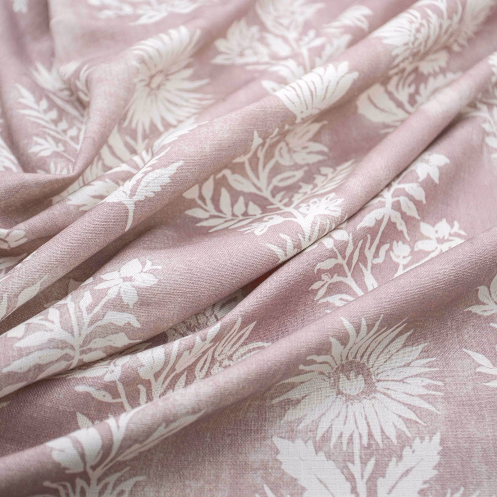 Dusty blush-pink floral fabric with ivory flowers and leafy stems in soft folds