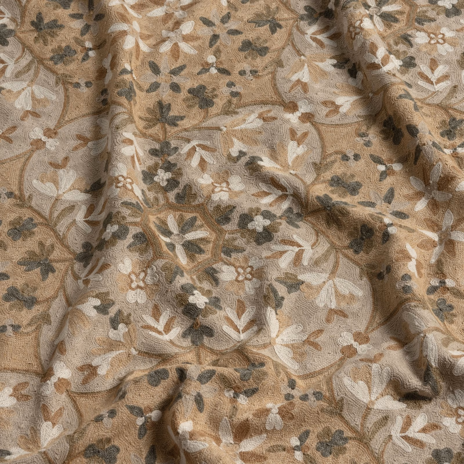 Warm taupe floral fabric with cream petals and charcoal-olive leaves in textured folds