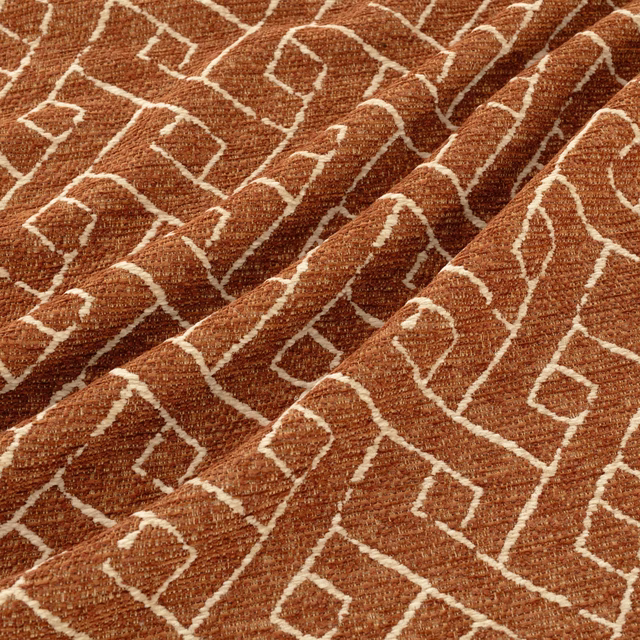 Rust-brown woven textile with cream maze-like geometric lines and tactile texture