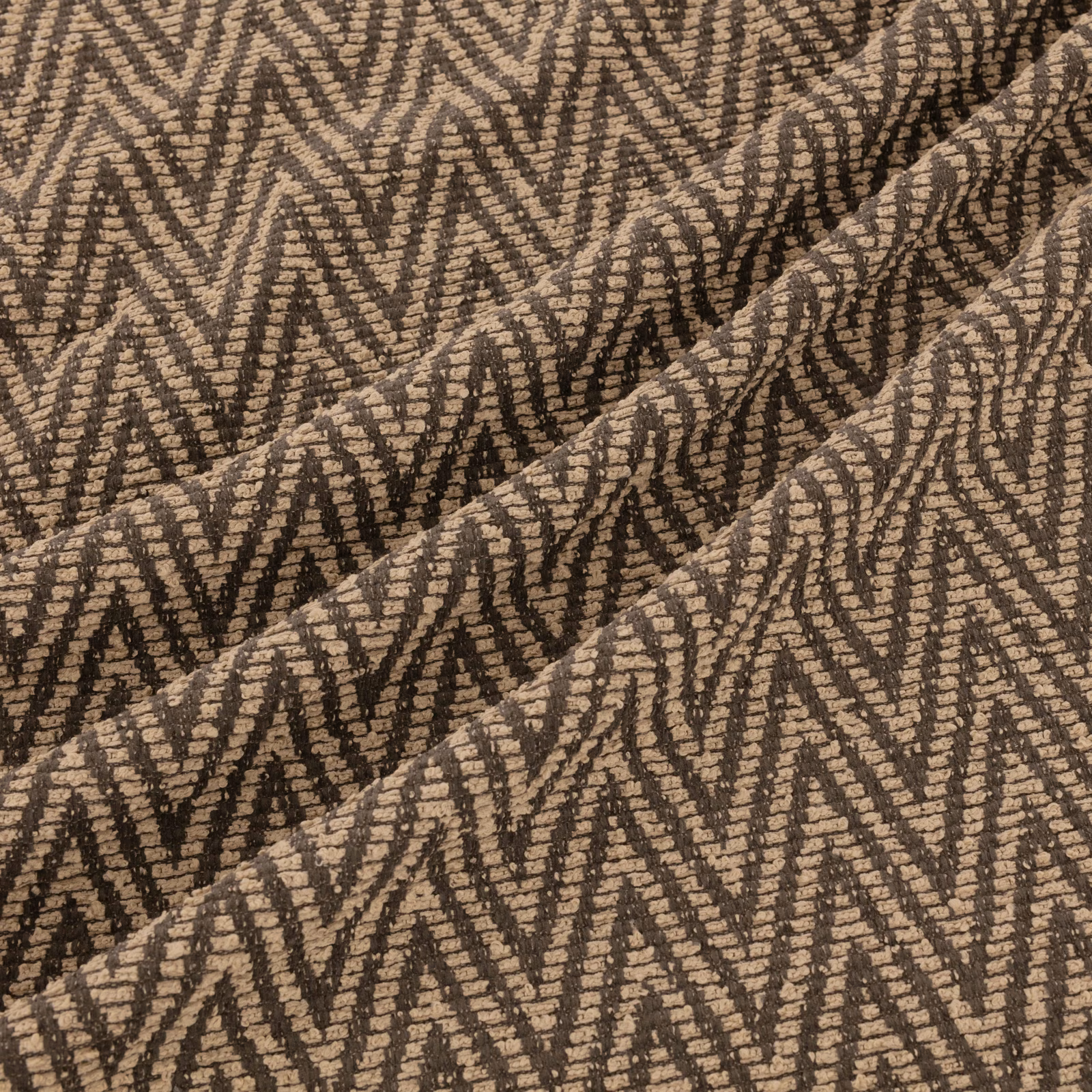 Warm taupe-brown woven textile with dark broken zigzags and raised ridged texture