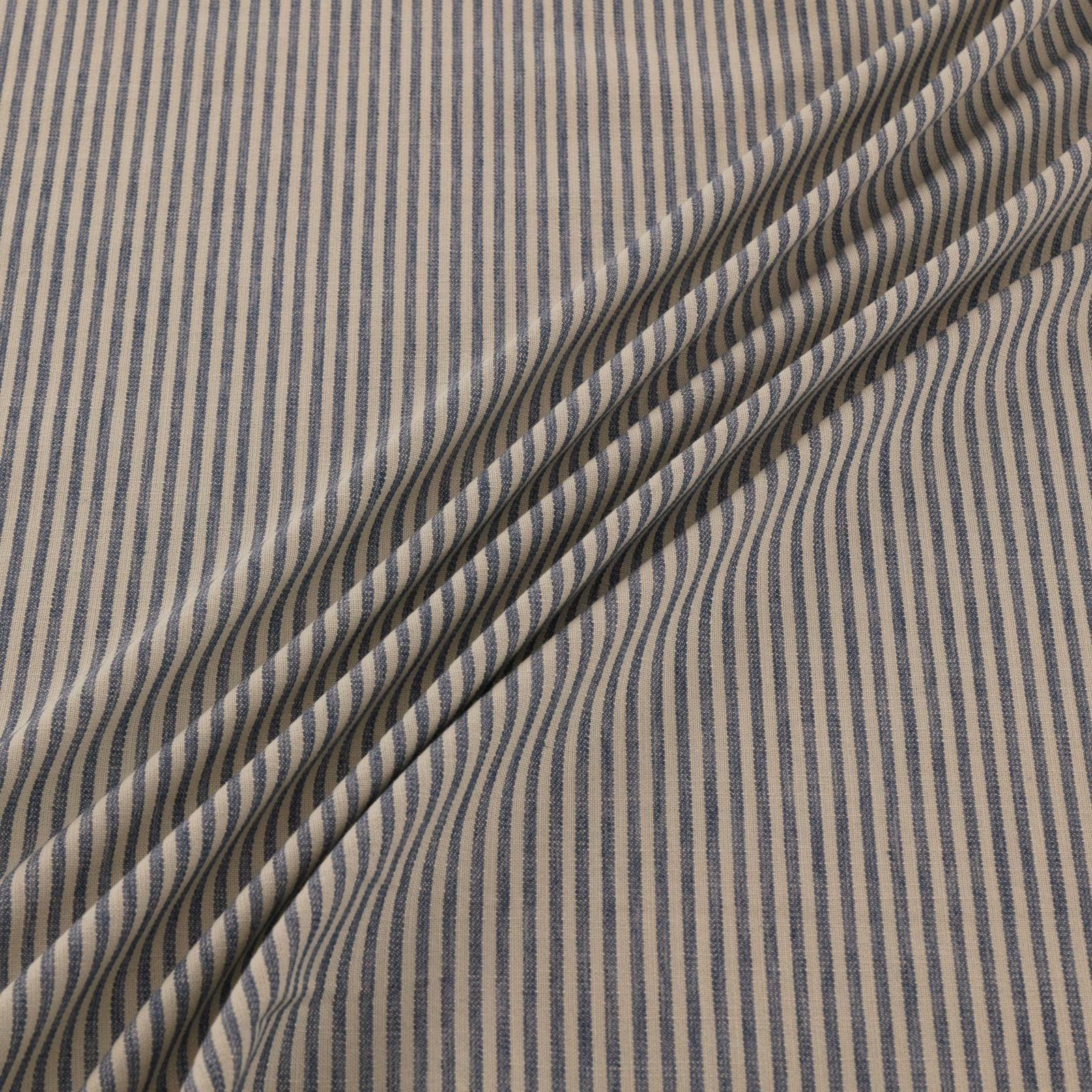 Taupe woven fabric with narrow undulating navy vertical stripes and folded texture