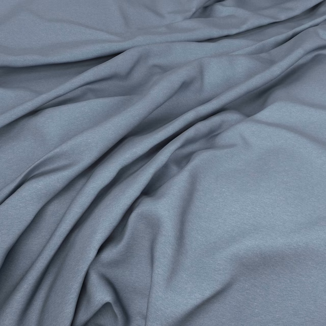 Soft blue-grey plain fabric draped into smooth, shadowed folds