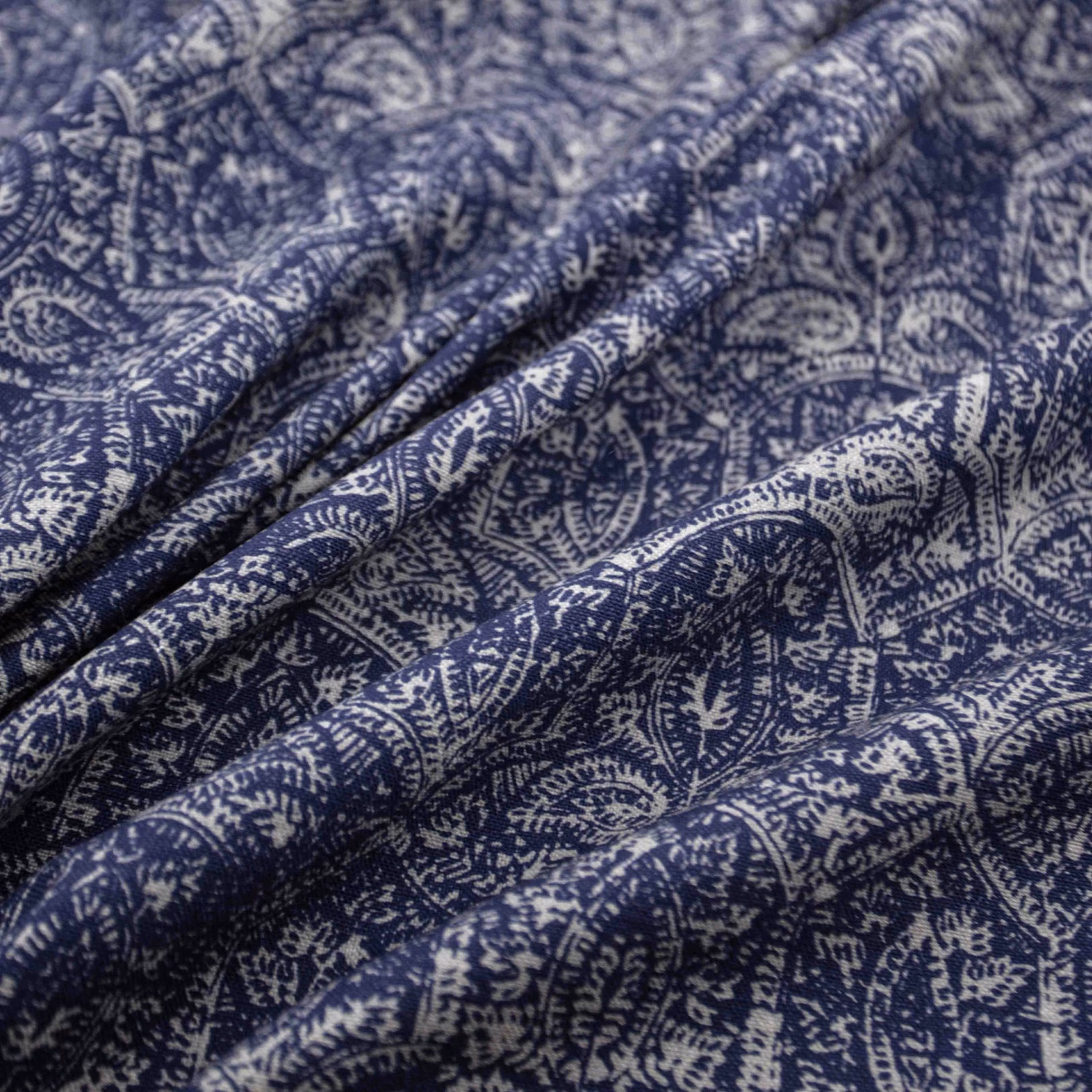 Deep indigo and ivory paisley fabric gathered into softly textured folds